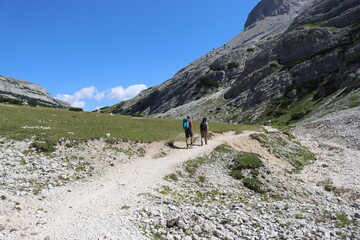 Obraz premium Val Badia, Italy-July 18, 2022: The italian Dolomites behind the small village of Corvara in summer days with beaitiful blue sky in the background. Green nature in the middle of the rocks.