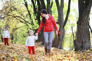 Naklejka premium Children for a walk in the autumn park. Leaf fall in the park. Family. Fall. Happiness.