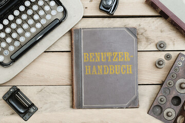 German word Benutzerhandbuch (user manual)on old book cover at office desk with vintage items
