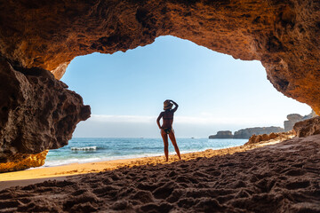 A woman on vacation at the beach cave in the Algarve, Praia da Coelha, Albufeira. Portugal