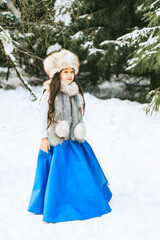portrait of beautiful cute little Asian girl in fur coat and fur hat standing in snowy forest in winter, winter holidays and having fun, Christmas vacation