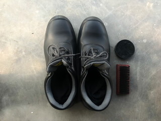 Black safety shoes next to a shoe brush and shoe polish. Ready to go to work