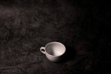 Obraz na płótnie Canvas small white empty ceramic coffee cup with blank copy space for design text or banner of brand, hot drink on grey black table.