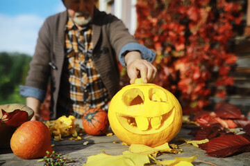 Autumn traditions and preparations for the holiday Halloween. A house in nature, a lamp made of pumpkins is cutting out at the table.