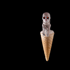 Halloween. A skeleton in an ice cream cone on a black background, Halloween concept