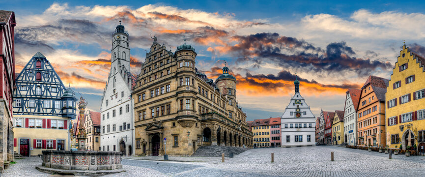 Die Fassade des Rathauses, der Ratsherrntrinkstube und anderer Gebäude rahmen den historischen Marktplatz der Altstadt von Rothenburg ob der Tauber in der Dämmerung  ein, bei stimmungsvollem Himmel
