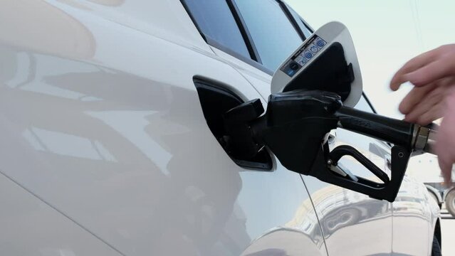Man filling gasoline in car at gas station. Fuel injector is inserted into the vehicle's gas tank at a petrol station. Refueling car by a person at a gas station. 