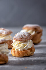 Homemade profiteroles with cream on light background