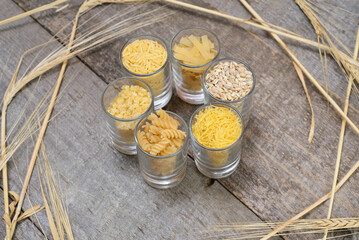 Various pasta on spoons over stone background. Top view with copy space