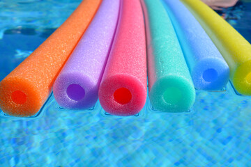 Polyethylene swim noodles floating in pool