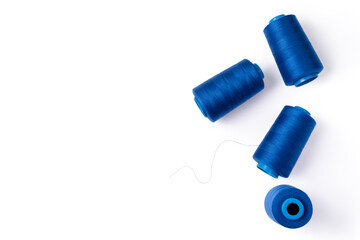Spools of blue sewing thread lie randomly. Electric blue threads. Tailoring concept. Top view. Copy...