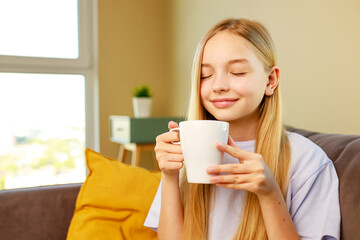 cute little blonde girl enjoy hot chocolate in living room before go to school eyes closed