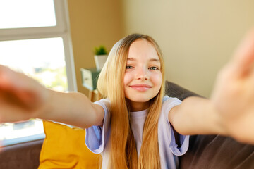 pre-teen girl making selfie photos on her smartphone in cozy living room at home