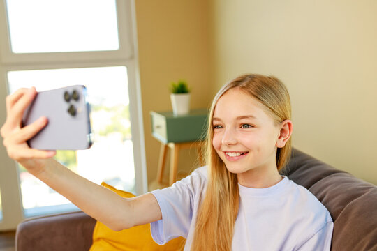 pre-teen girl making selfie photos on her smartphone in cozy living room at home