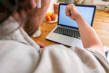 man's hand shakes his fist at a laptop monitor. selective focus