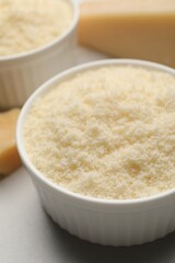 Bowl with grated parmesan cheese on white table, closeup
