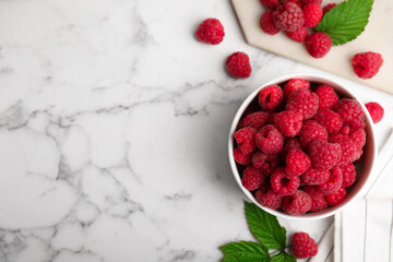 Bowl with fresh ripe raspberries on white marble table, flat lay. Space for text
