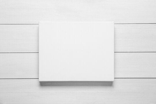 Blank canvas on white wooden background, top view. Space for design