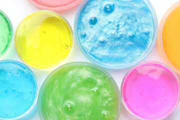 Colorful slimes in plastic containers on white background, top view. Antistress toy