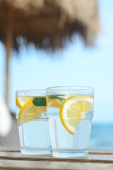 Refreshing water with lemon and mint on wooden table outdoors