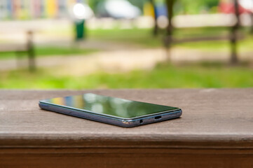 Smartphone on wooden bench outdoors, space for text. Lost and found