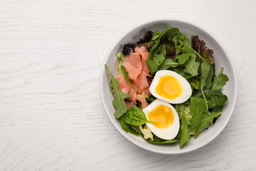 Delicious salad with boiled egg, salmon and arugula on white wooden table, top view