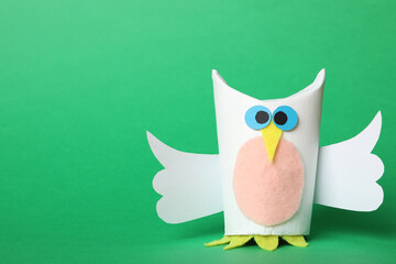 Toy owl made of toilet paper hub on green background. Space for text