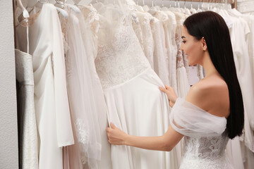 Young woman choosing wedding dress in salon