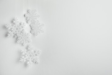 Beautiful decorative snowflakes hanging on light grey background, space for text