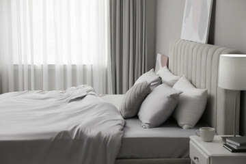 Cozy bed with soft silky bedclothes in light room