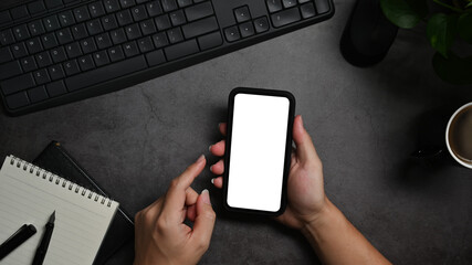 From above view man using mobile phone on black stone table. Blank screen for your text