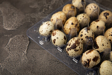 Quail eggs in plastic packaging on a black background. Natural products. Place for text. fresh eggs