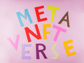 NFT METAVERSE text on pink background. Inscription Nft Metaverse with multi-colored paper letters. Metaverse, virtual reality and blockchain technology