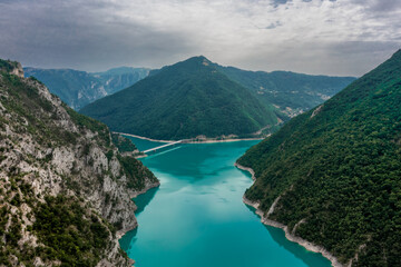 Piva Lake - Amazing Mountain View in Montenegro / Alps Landscape - turquoise blue water on Balkan with main Mountain in the middle and bridge aerial drone shot