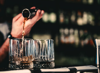 Bartender pouring whiskey on glass in bar
