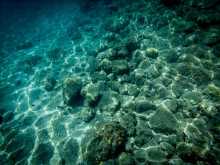Underwater picture of stone sea bottom with waves refraction visible on the sea floor