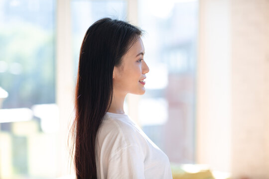 Portrait profile of smiling asian woman on apartment interior background.