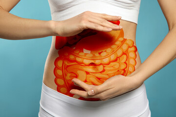 Closeup view of woman with illustration of abdominal organs on her belly against light blue...