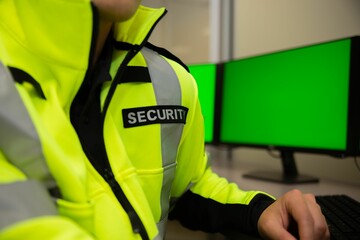 Closeup shot of a security officer with a yellow jacket sitting at the office in front of a computer