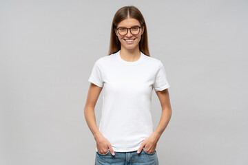Young woman in casual white t-shirt standing with hands in pockets, template or mockup for logo