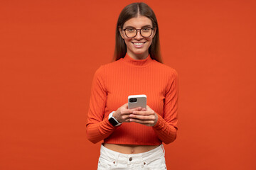 Portrait of woman surfing on phone online isolated on orange background