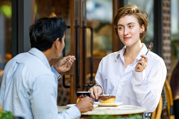 Caucasian couple have a date at european style cafe bistro enjoying morning vibe around the city square with sweet pastry and a cup of coffee