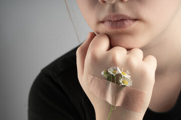 A daisy flower is glued to a child's hand with a band-aid. The concept of a photo of life continues