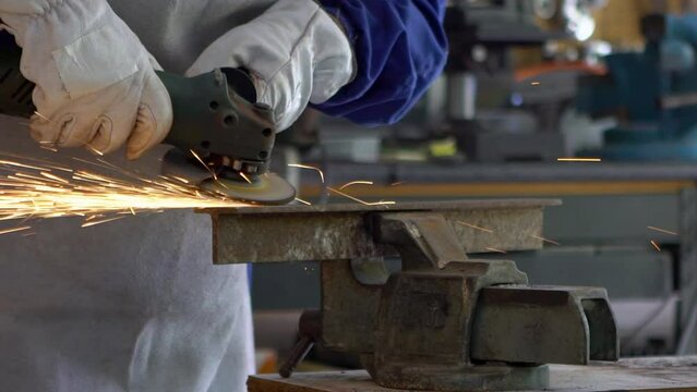 Slowmotion of craftsman grinding metal with disk grinder in workshop. Worker cleaning the steel seam. Cutting grinding wheel cut a piece of iron with sparks fly in different directions.