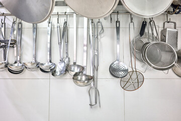 Kitchen Ladles, Cooking Skimmers and others Cookware hanging on the wall of a professional kitchen. - Powered by Adobe