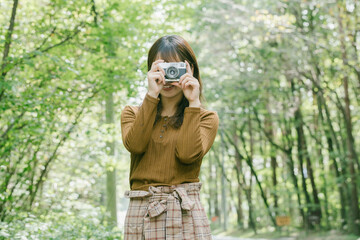 日本の女性がカメラを持って緑の中にいる　woman photographer