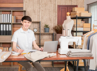 Young Business owner working fashion designer using laptop for find new collection dress, Asian man work from home design on notebook, smiling entrepreneur working on laptop at workplace.