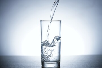 Photo of pouring water into a glass of water