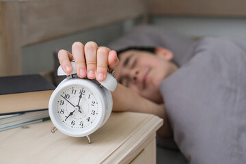 Smiling boy reaches for the alarm clock to turn it off. Morning of the schoolboy