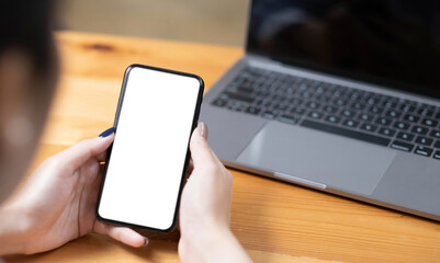 hand woman using a telephone, empty screen smart phone and computer on wooden table top view.